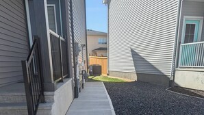 Eine Wohnstraße mit Häusern, einem Betonweg und einem Kiesgrundstück.