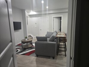 Una sala moderna con un sofá gris, una mesita redonda y una mesa de centro.