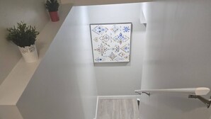 Eine Treppe mit Handlauf, Wandverkleidung mit Muster und Topfpflanzen.
