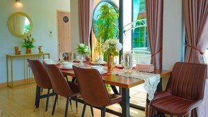 A dining area with a table set for four, surrounded by chairs, a mirror, and a potted plant. - MK Land Pool Villa Khaokho (Khao Kho)