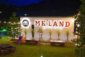 Un bâtiment sur lequel on peut lire les inscriptions « MKLAND » et « Wazai Iwano », avec une terrasse et des plantes en pot à l’extérieur.