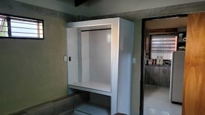 A room with a bed, a wardrobe, a small window, and a door leading to a kitchen. - Las Lomitas Residence (Ñemby)