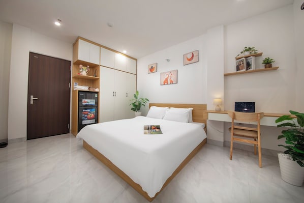 A bedroom with a bed, a desk, a wardrobe, a refrigerator, and a door. - Ly Apartment - Yen Phu str (Tay Ho)