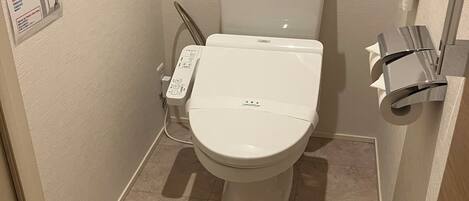 Un baño pequeño y moderno con inodoro, secamanos y toallero.