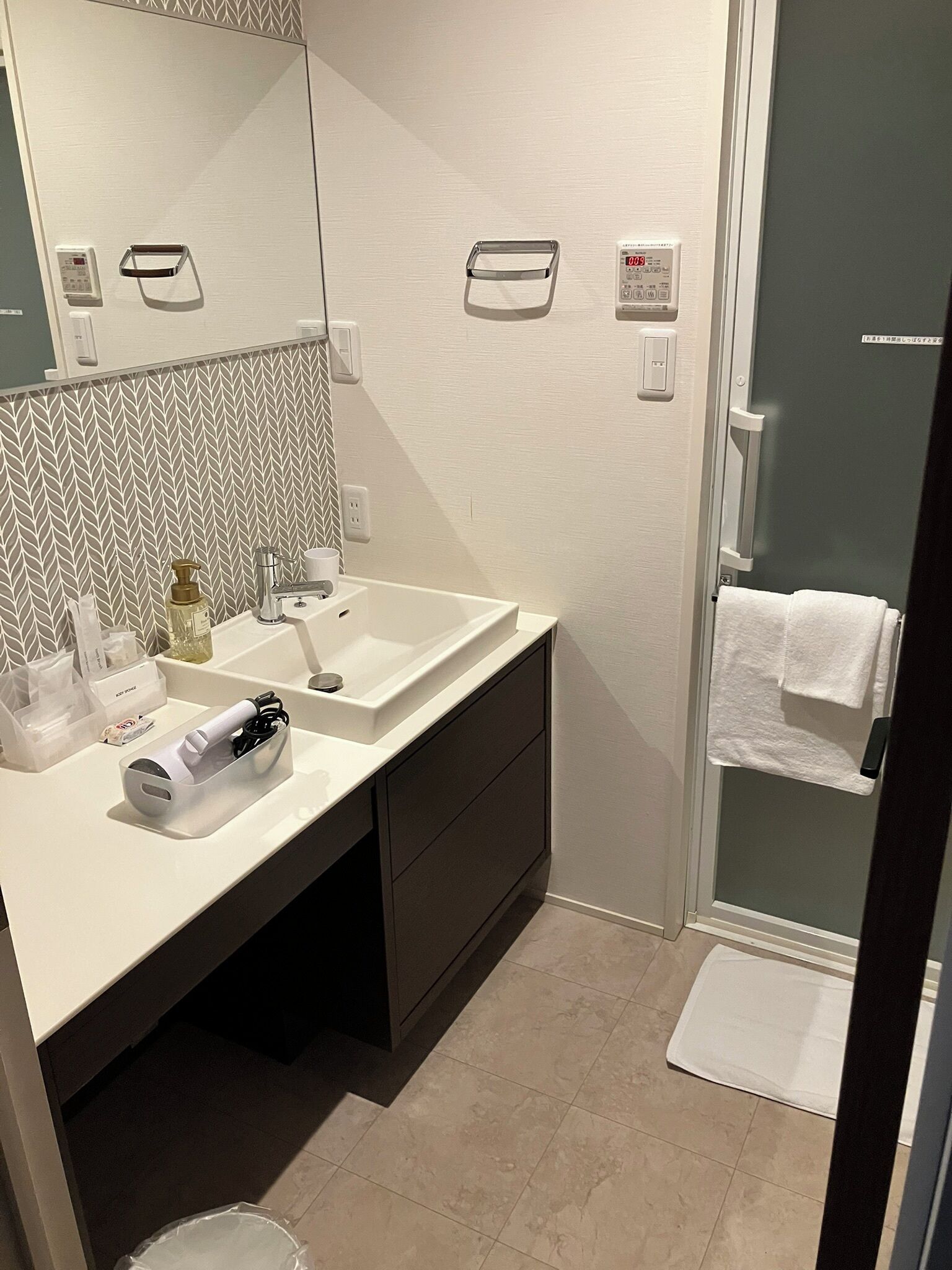 A modern bathroom with a white sink, dark cabinet, and a glass shower enclosure.