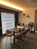 Uma área de refeições moderna com uma mesa redonda, quatro cadeiras e uma máquina de café.