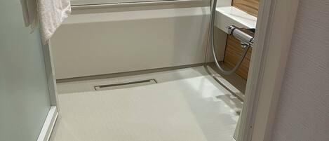 Un baño con una bañera blanca, zona de ducha y una toalla blanca colgada en la pared.