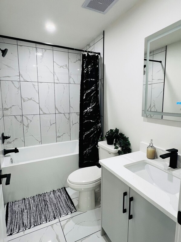 A bathroom with a bathtub, toilet, sink, and mirror.