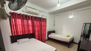 A bedroom with two single beds, a fan, an air conditioning unit, a mirror, and a small table. - Airport Residencies (Katunayake)
