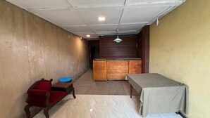 A room with a bed, a small table, a red chair, and a wooden cabinet. - Airport Residencies (Katunayake)