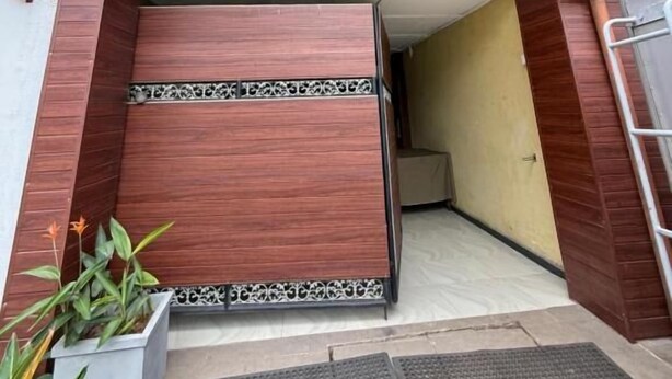 A modern building entrance with a sloped roof, a metal gate, and a concrete pathway leading to the door. - Airport Residencies (Katunayake)
