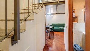 A staircase leading to a living area with a green sofa, dining table, and chairs. - Elegant Loft in Citylife Wifi - A/C - (Milan)