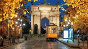A tram at a historic archway with autumn leaves, a tram stop, and a clear night sky. - Elegant Loft in Citylife Wifi - A/C - (Milan)