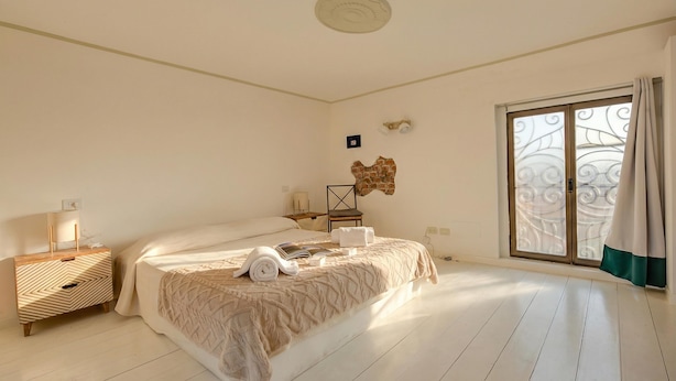 A bedroom with a bed, bedside table, lamp, and a window with curtains. - Elegant Loft in Citylife Wifi - A/C - (Milan)