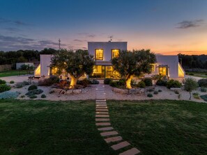A modern two-story house with a well-maintained garden and a stone pathway leading to the entrance. - Tenuta Serra De Citris By Tecla Collection (Polignano a Mare)