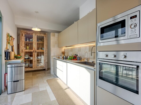 Eine moderne Küche mit Edelstahlgeräten, einem eingebauten Ofen und einem Holzkasten mit Glastüren.