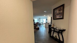 Un passadís amb terra de fusta que condueix a una zona de dinar amb taula i cadires.
