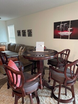Un comedor con una mesa redonda y cuatro sillas, un sofá y decoración en la pared.