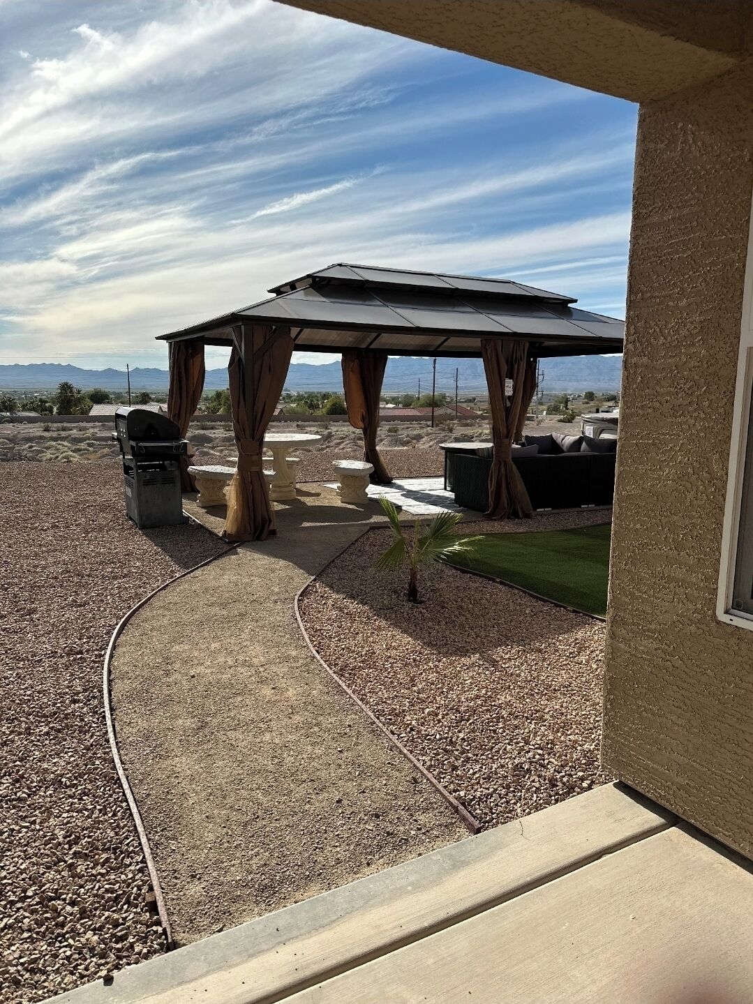 A covered patio with a grill, outdoor seating, and a view of mountains.