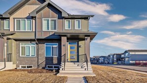 A two-story house with a front porch, a visible garage, and a clear sky. - Perfect 3-bedroom house in lovely Calgary for your getaway (Calgary)