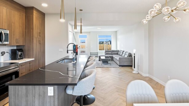 A modern kitchen with a central island, wooden cabinets, and a dining area with a sofa and chairs. - Perfect 3-bedroom house in lovely Calgary for your getaway (Calgary)