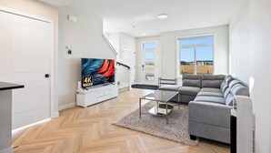 A modern living room with a flat-screen TV, grey sofa, and a herringbone-patterned floor. - Perfect 3-bedroom house in lovely Calgary for your getaway (Calgary)