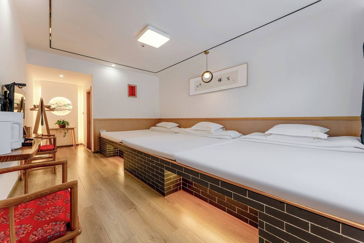 A hotel room with a bed, a desk, a chair, and a small table with a plant.