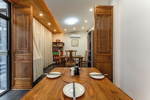 Un comedor con una mesa de madera, sillas y una estantería.