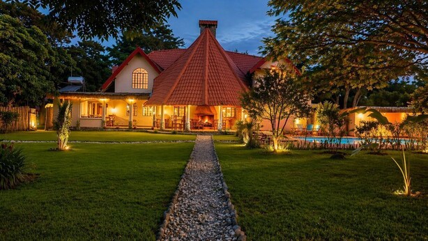 A house with a red roof, a swimming pool, and a well-maintained lawn.