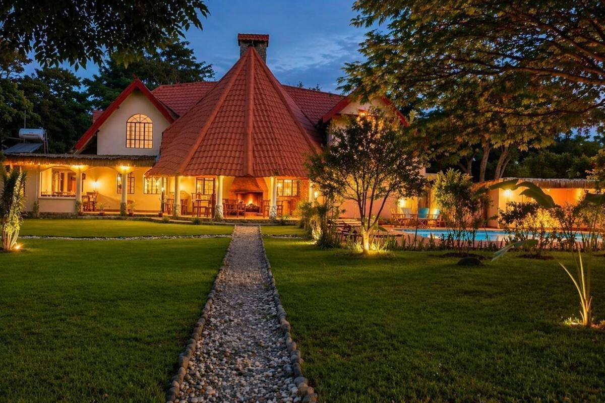 A house with a red roof, a swimming pool, and a well-maintained lawn.