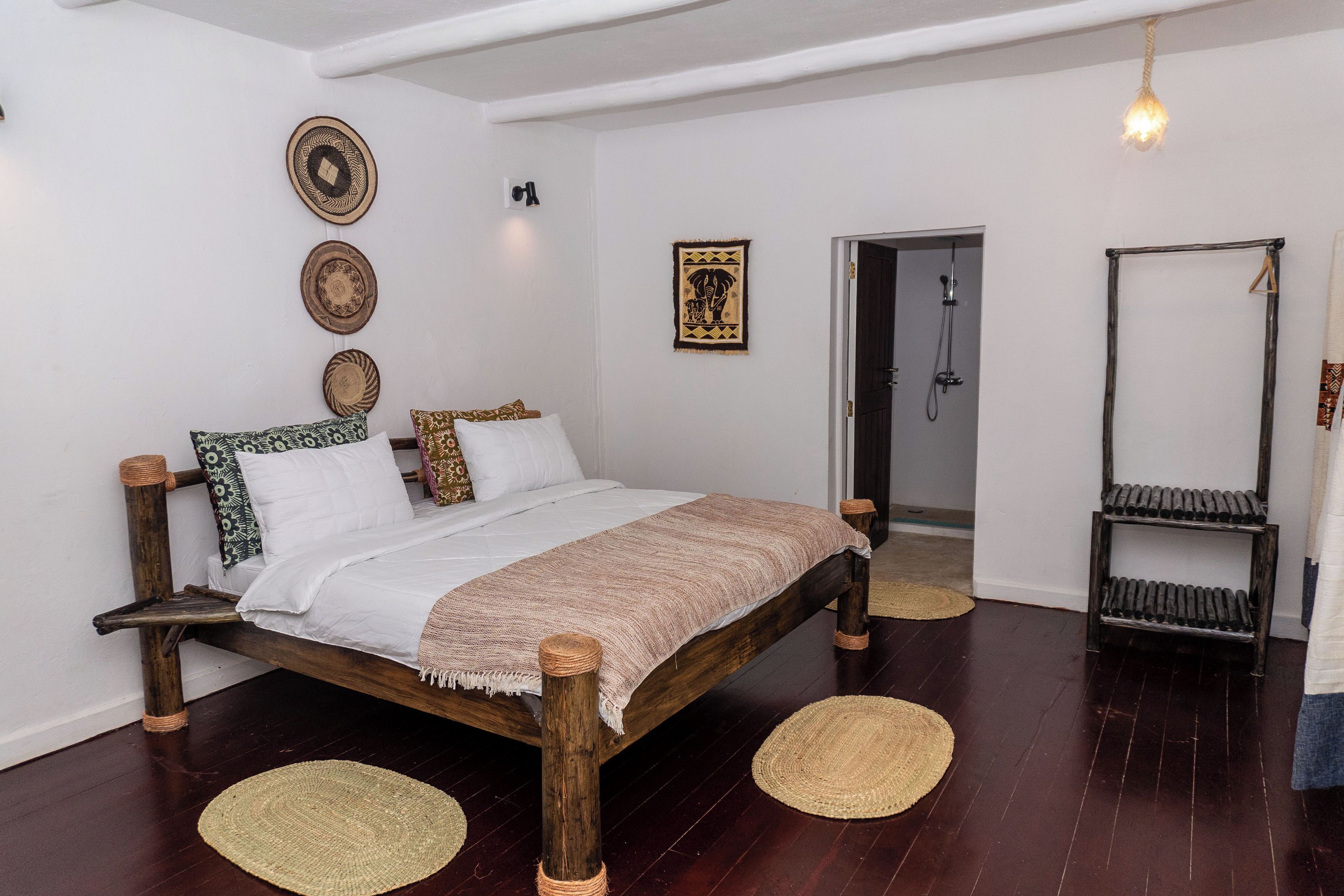 Ein Zimmer mit einem hölzernen Bett, gewebten Teppichen und einer hängenden Leuchte.