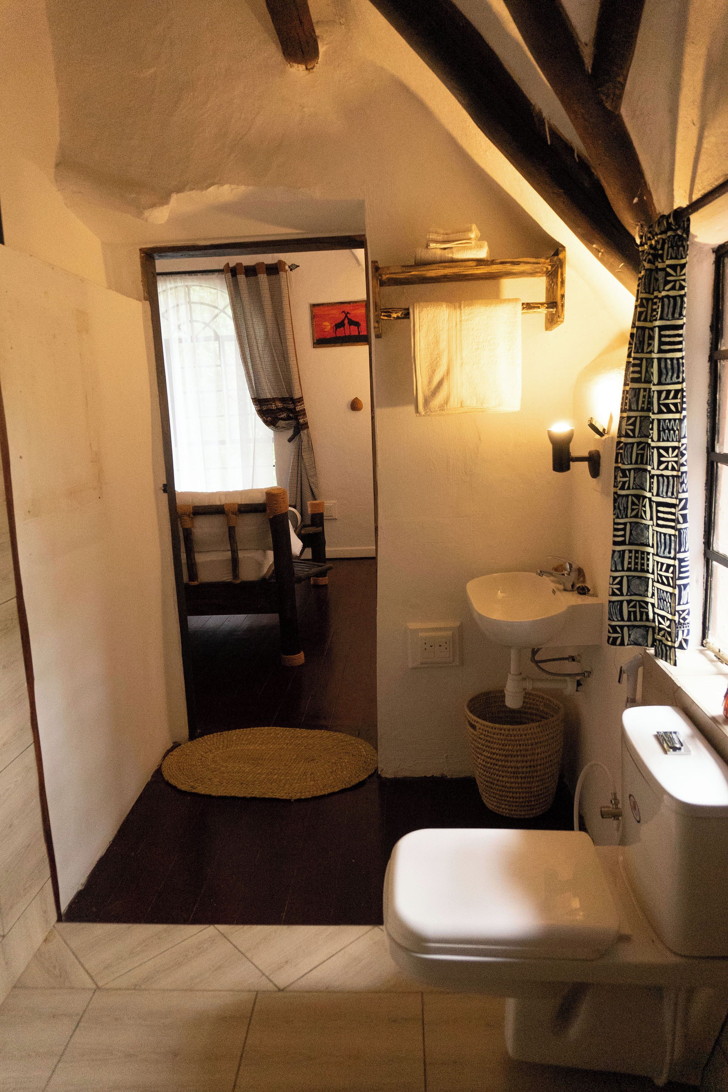 A small bathroom with a toilet, sink, and a window with patterned curtains.