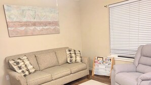 A living room with a sofa, a chair, a ceiling fan, a window with blinds, and a rug. - Superb 3-bedroom condo in Wellman within walking distance from two playgrounds. (Wellman)