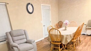 A dining area with a table, chairs, a clock, and a door. - Superb 3-bedroom condo in Wellman within walking distance from two playgrounds. (Wellman)