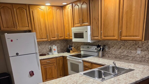 A kitchen with wooden cabinets, a refrigerator, a microwave, an oven, and a granite countertop. - Superb 3-bedroom condo in Wellman within walking distance from two playgrounds. (Wellman)