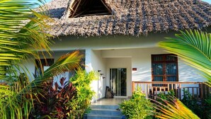 Ein Haus mit einem Strohdach, einer Veranda und einer Treppe, die zum Eingang führt.