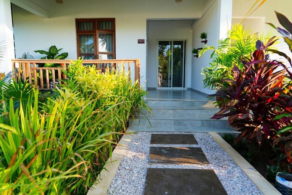 A hotel entrance with a wooden deck, a glass door, and a pathway leading to the entrance.