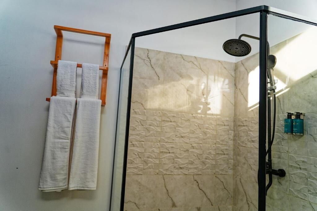 A shower with a glass door, a towel rack with two towels, and a textured wall.