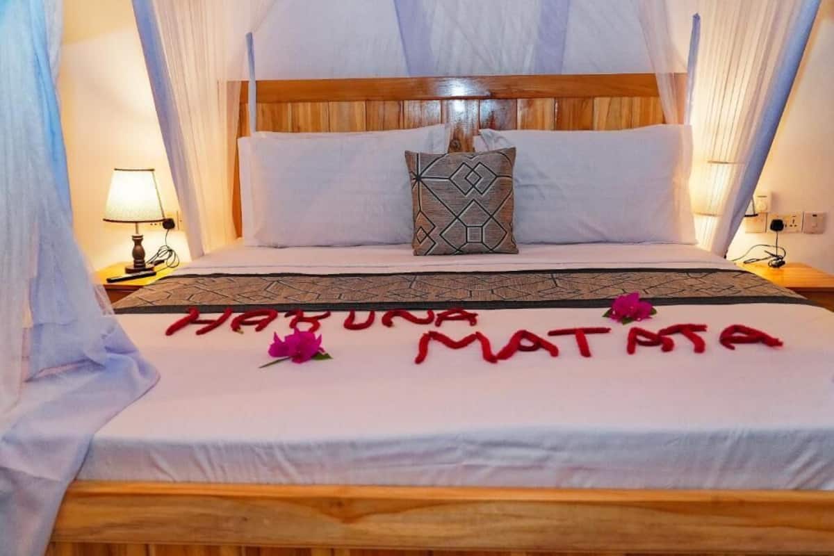 A bed with a canopy, a bedside lamp, and a decorative pillow.