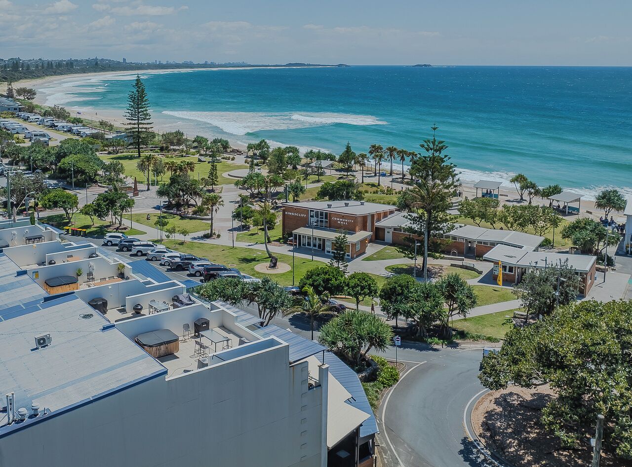 A coastal area with a beach, a community center, and a parking lot.