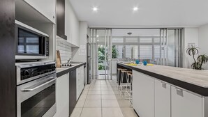 Een moderne keuken met een magnetron, oven en barkrukken.