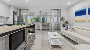 Een moderne keuken met een eethoek, een witte bank en een salontafel.