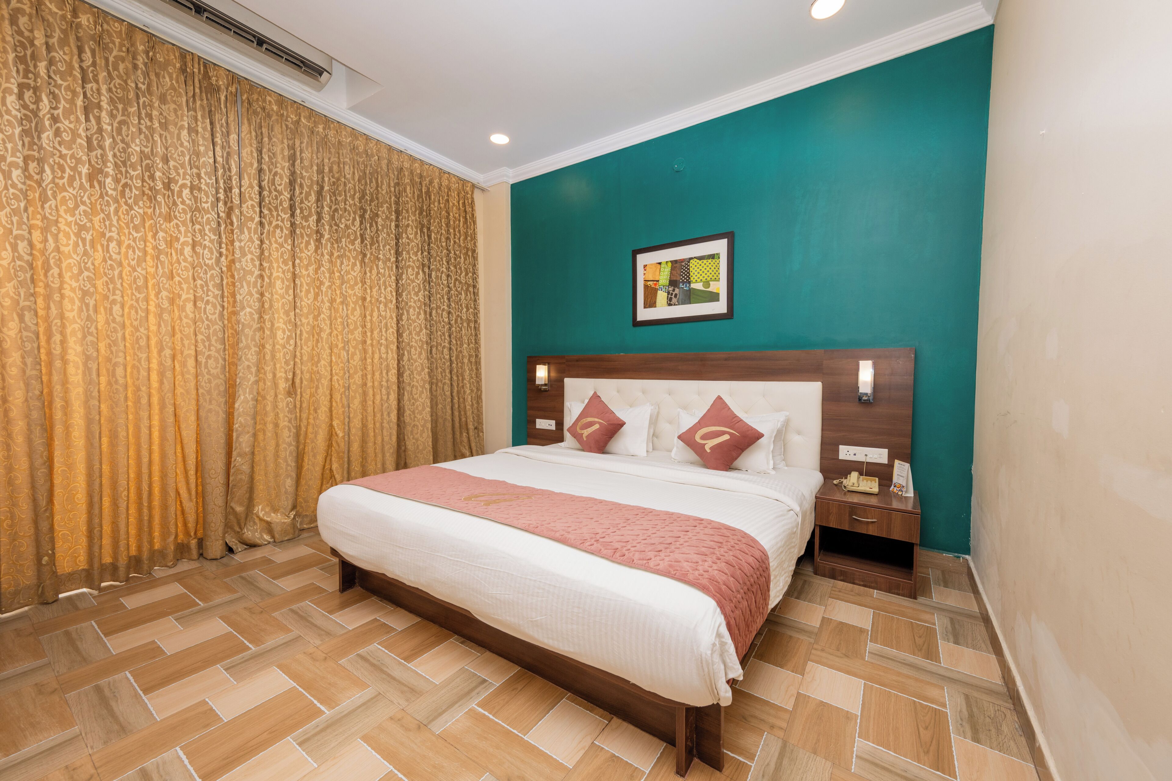 A hotel room with a large bed, a nightstand, a wall-mounted clock, and a framed picture.