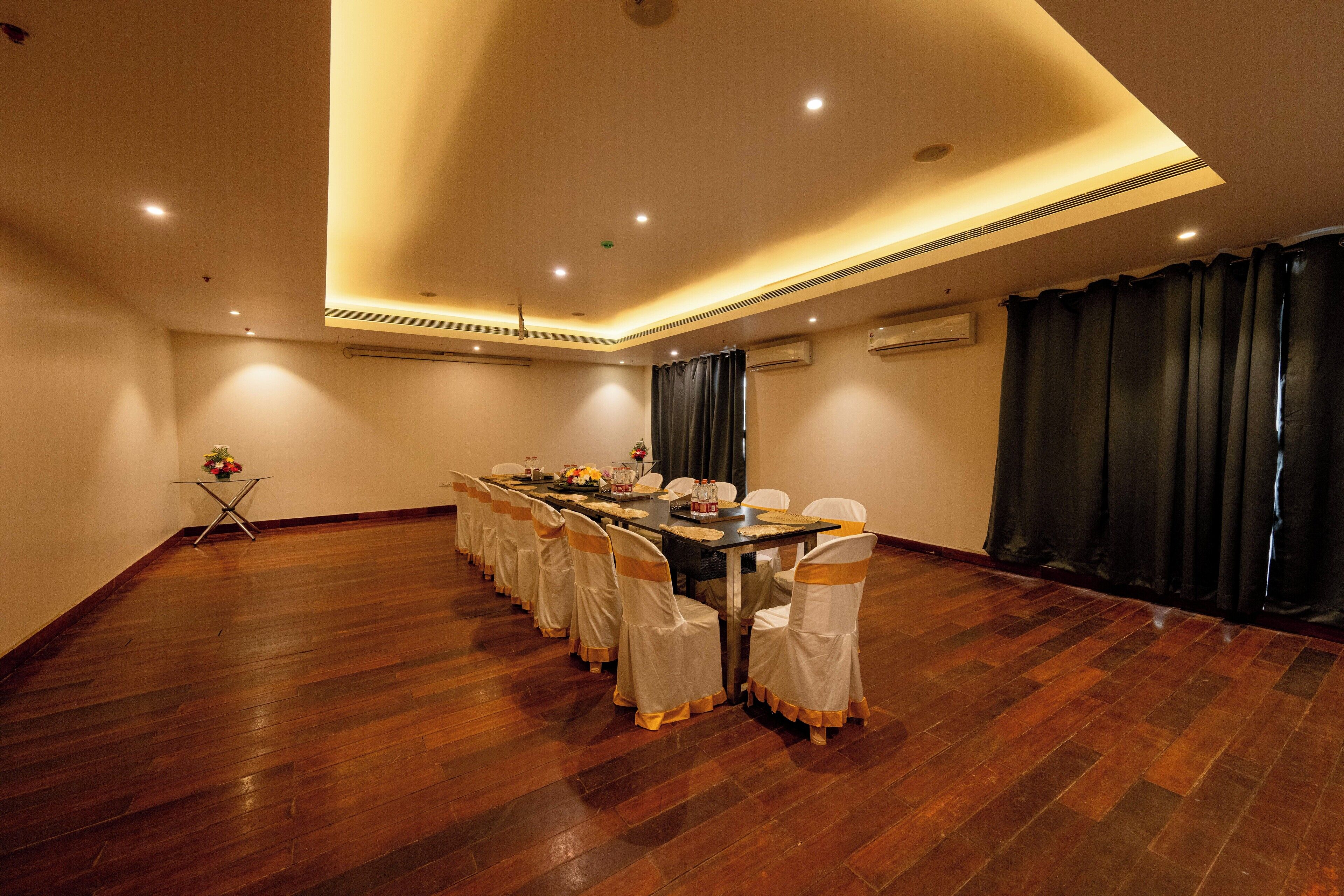 A conference room with a long table, chairs, and a small table with flowers.