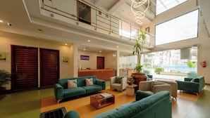 A spacious lobby with multiple seating areas, a reception desk, and large windows offering views of the outside. - Astra Hotels & Suites Marathahalli Spice (Bengaluru)