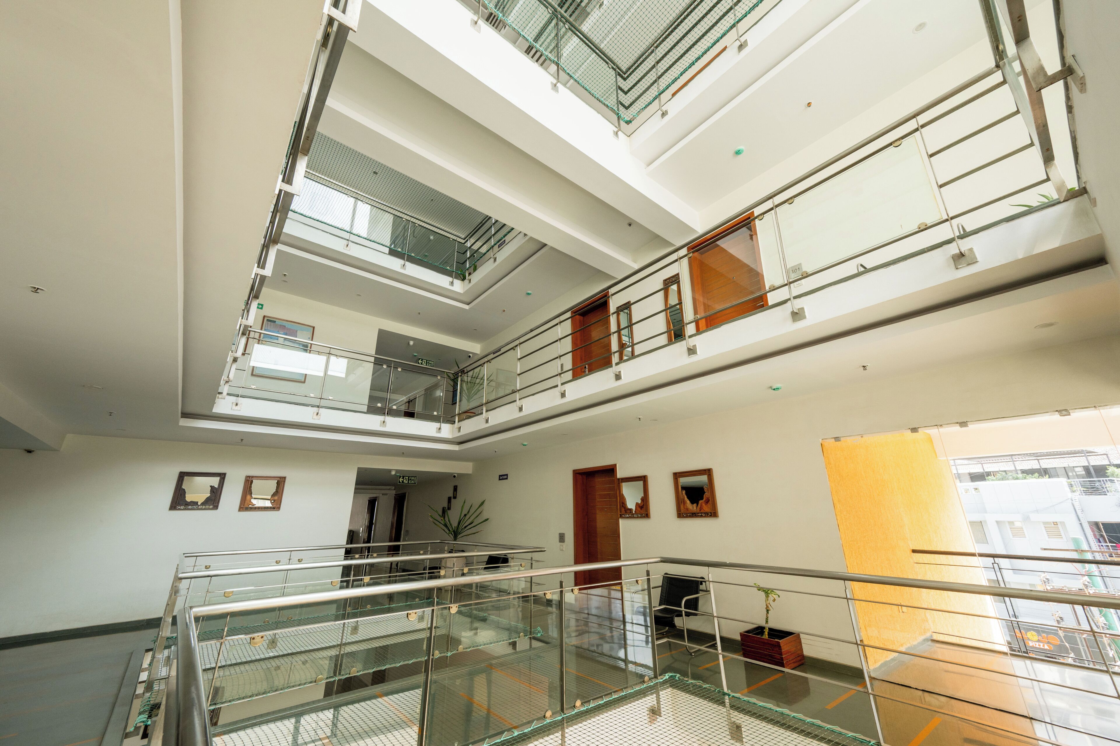 Un interior de varios niveles con barandillas de vidrio, una escalera y vistas al exterior.