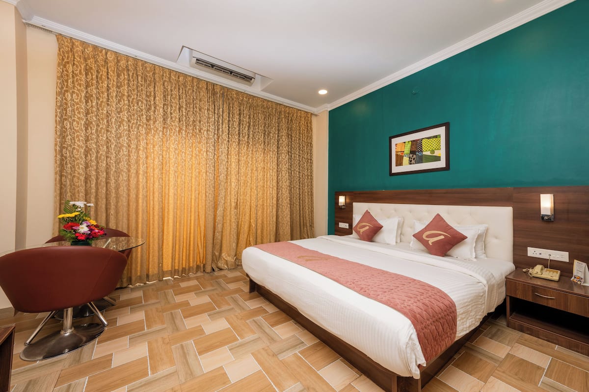 Une chambre d’hôtel avec un grand lit, un bureau, une chaise et un rideau.
