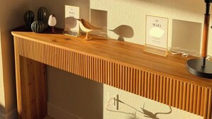 En sminkbord av trä med en rund spegel, en inramad skylt som visar Wi-Fi-symbolen och en lampa.