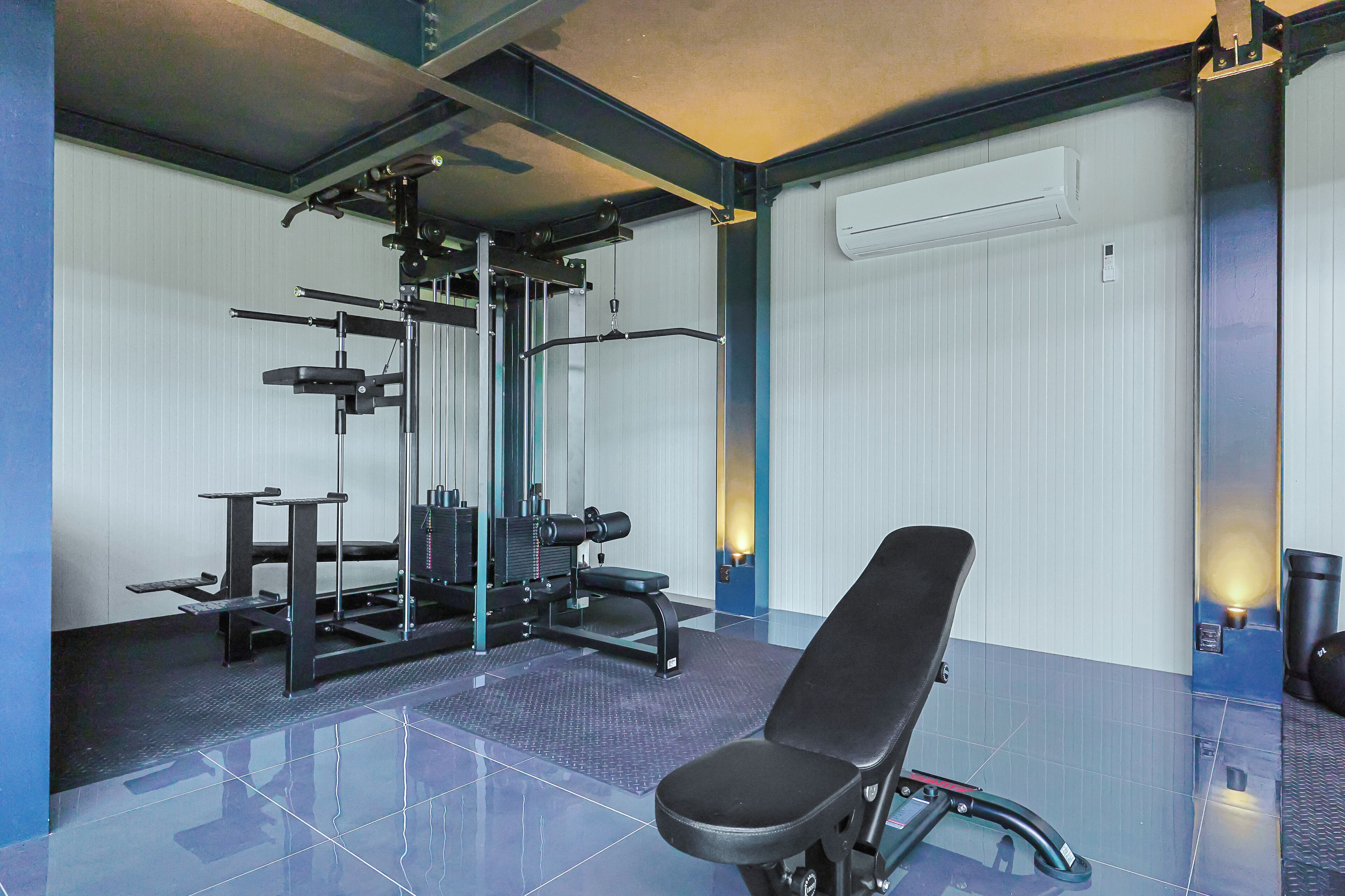 A gym with a bench, weight machines, and a mirrored wall.