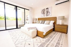 Ein modernes Schlafzimmer mit einem großen Bett, einem Holzkopfende und Blick durch eine Schiebeglastür.